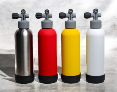 Four Deep stainless steel water bottles in red, silver, yellow, and white, designed for scuba divers and ocean lovers.